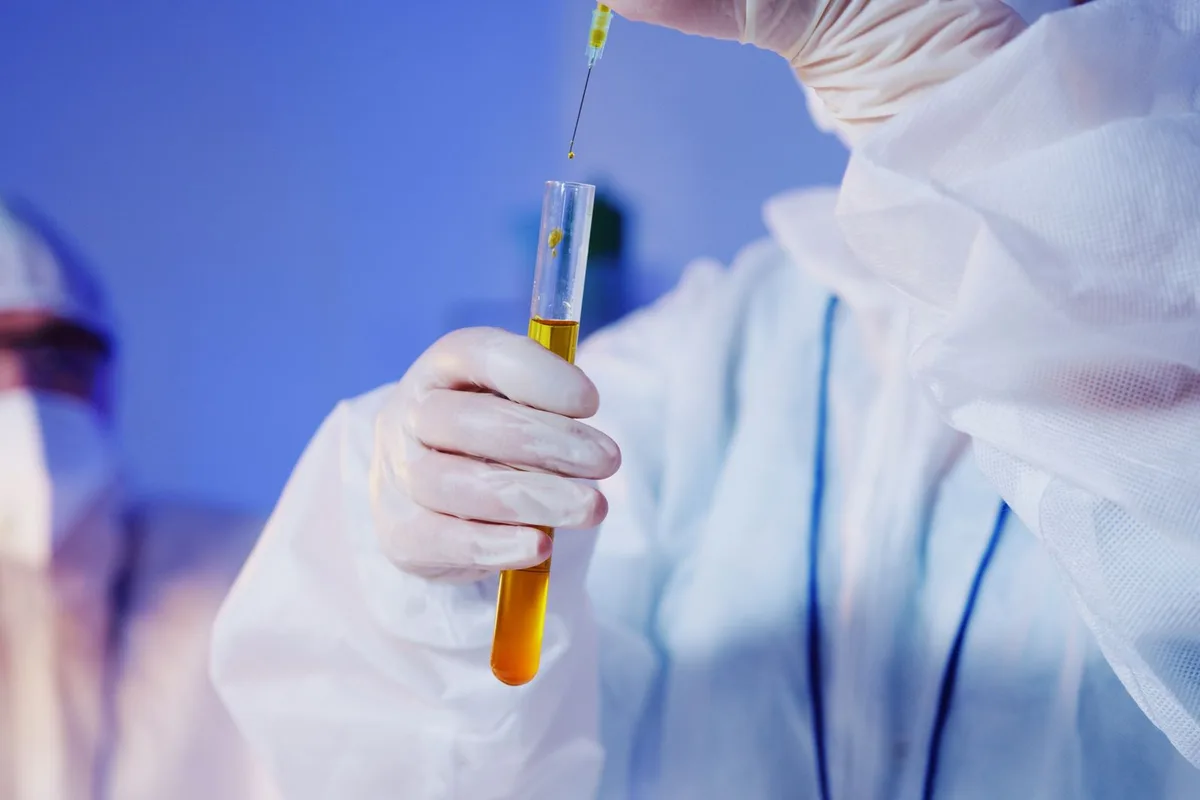 A gloved hand holding a sample tube in a genetics laboratory