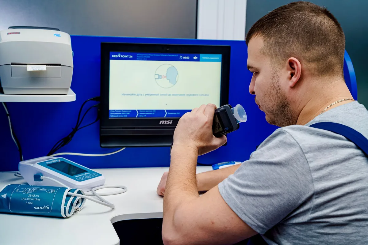 A man breathing out into a breath test device